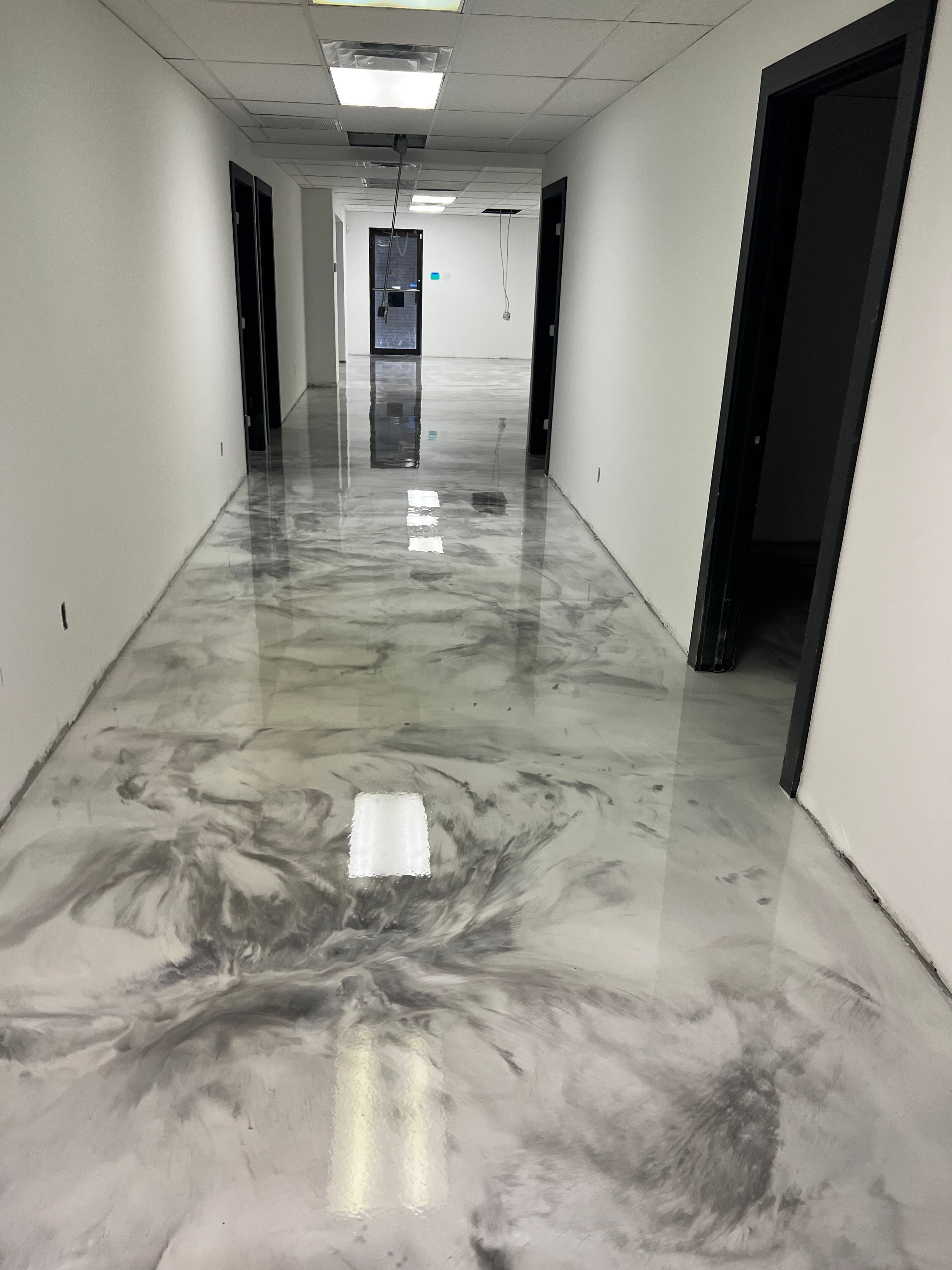 Modern hallway with white walls and a glossy, marbled grey and white epoxy floor.