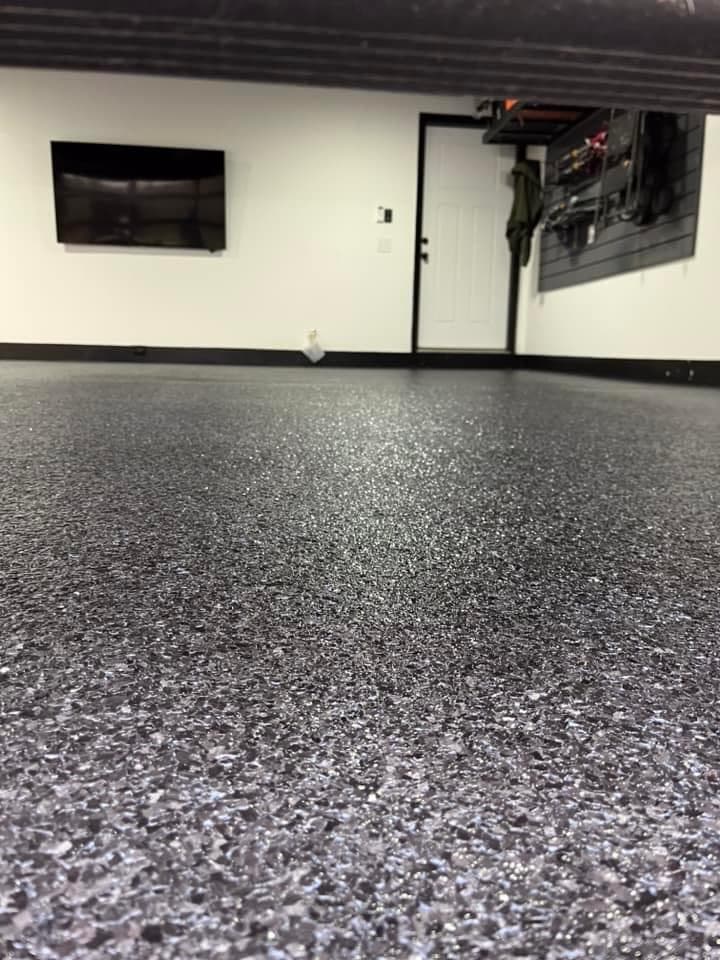 Close-up of a glossy dark gray speckled epoxy floor in a clean white garage.
