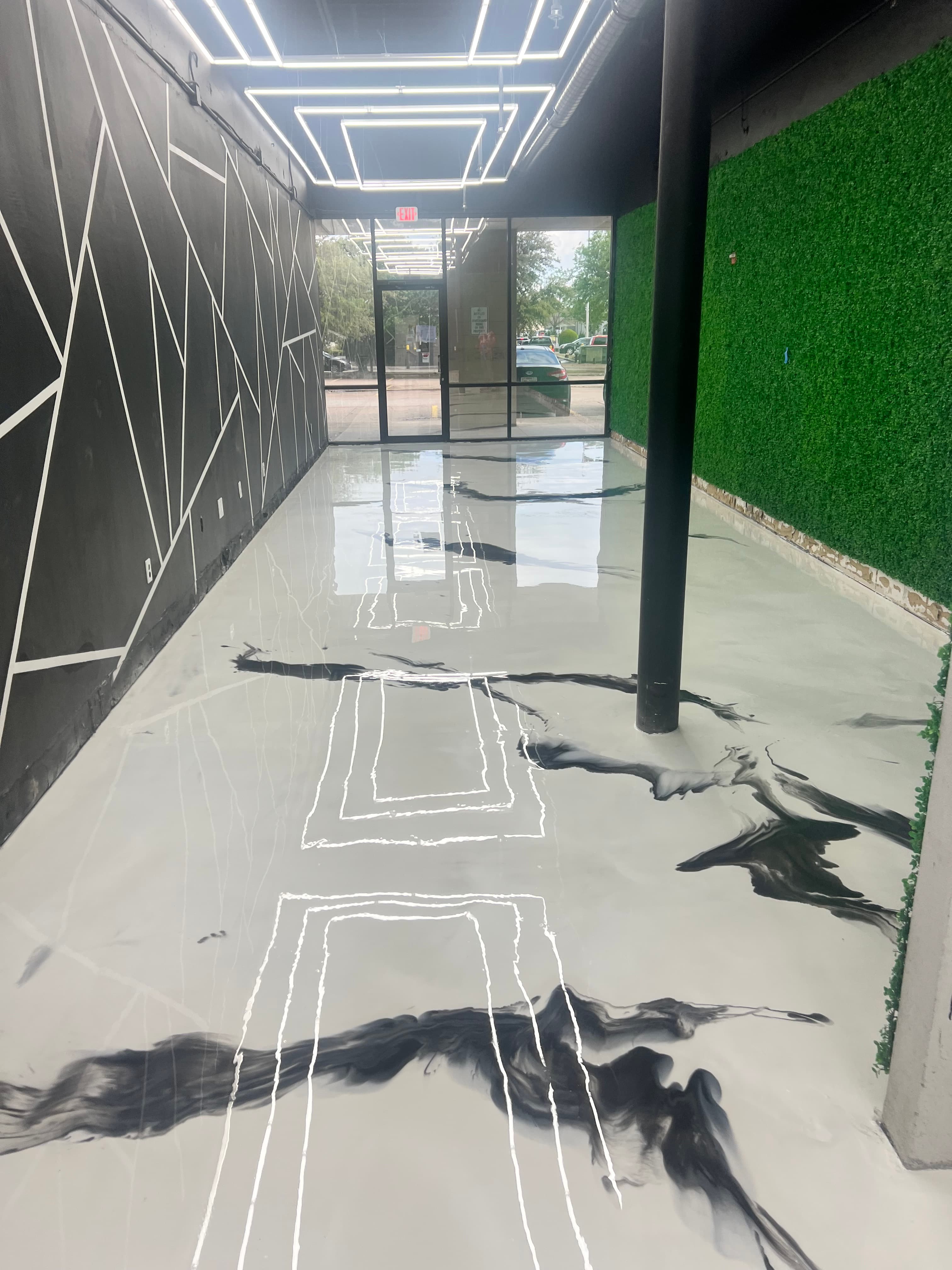 Modern room featuring white marbled epoxy floors, geometric black walls, and rectangular LED lighting.